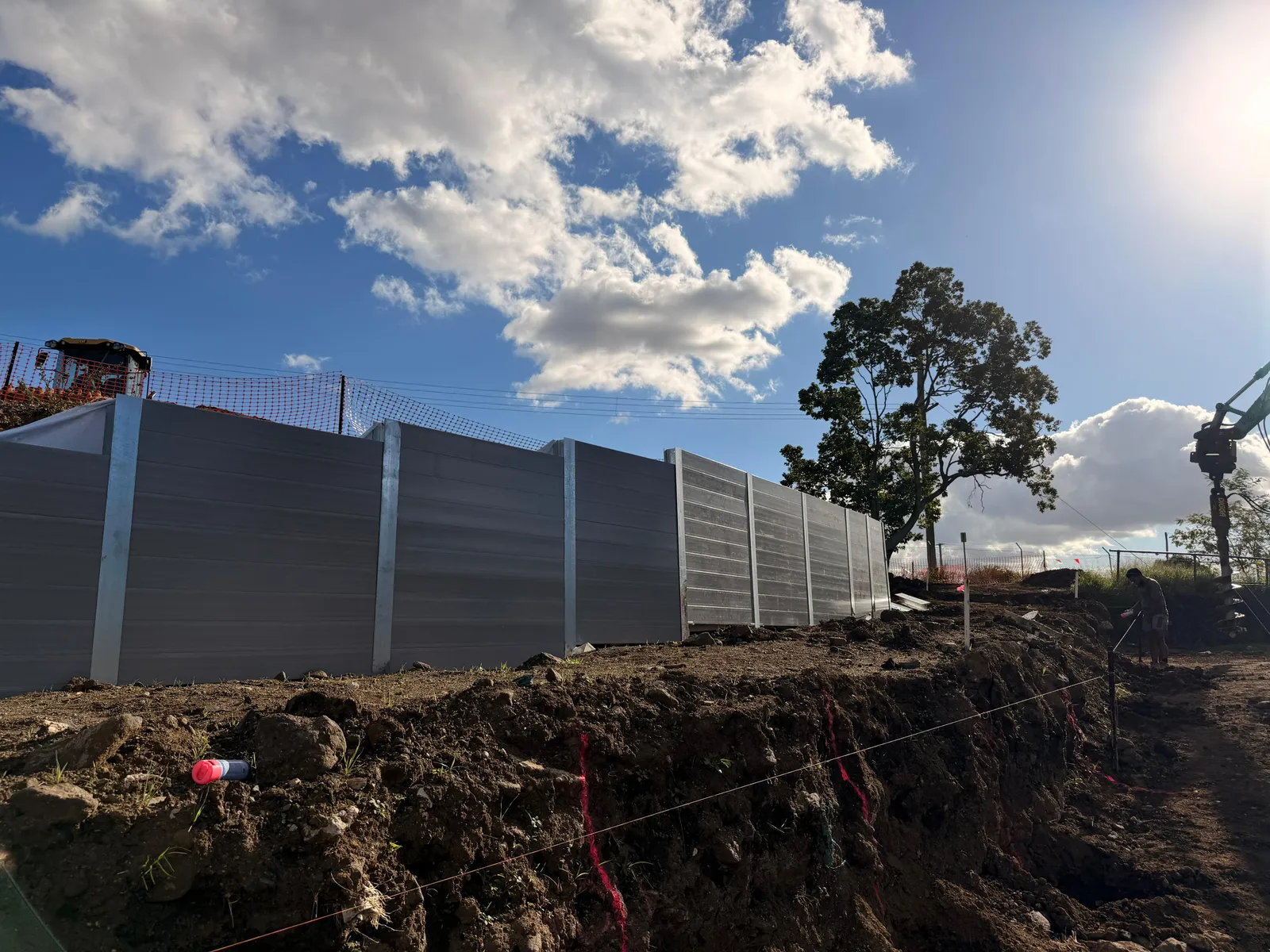Excavator drilling foundations for a SuperSleeper retaining wall